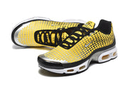 Angled view of yellow, black, and silver Nike Air Max Plus sneakers.