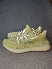 Pair of green low-top sneakers shown from a side angle with white laces and translucent ribbed soles.