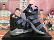 Angled view of the pair showing the layered strap system, white Swoosh branding, black uppers, purple accents, and light-colored soles.