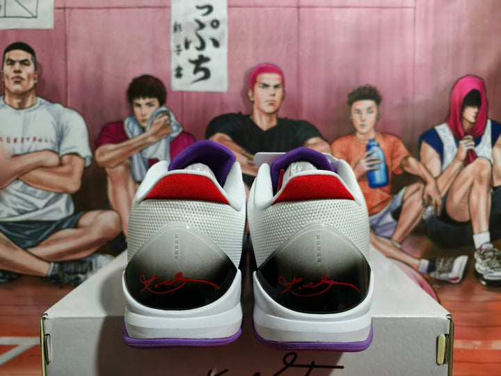 Rear view of white and purple Nike basketball sneakers showing red heel accents, black heel panels, purple outsoles, and Kobe-style signature details.