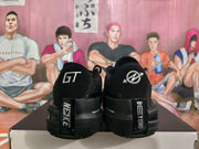 Rear view of the black sneakers showing GT markings, heel overlays and textured rubber outsoles.