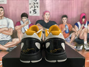Rear view showing black heel panels, white inserts, gold collar lining, and gold signature-style markings.