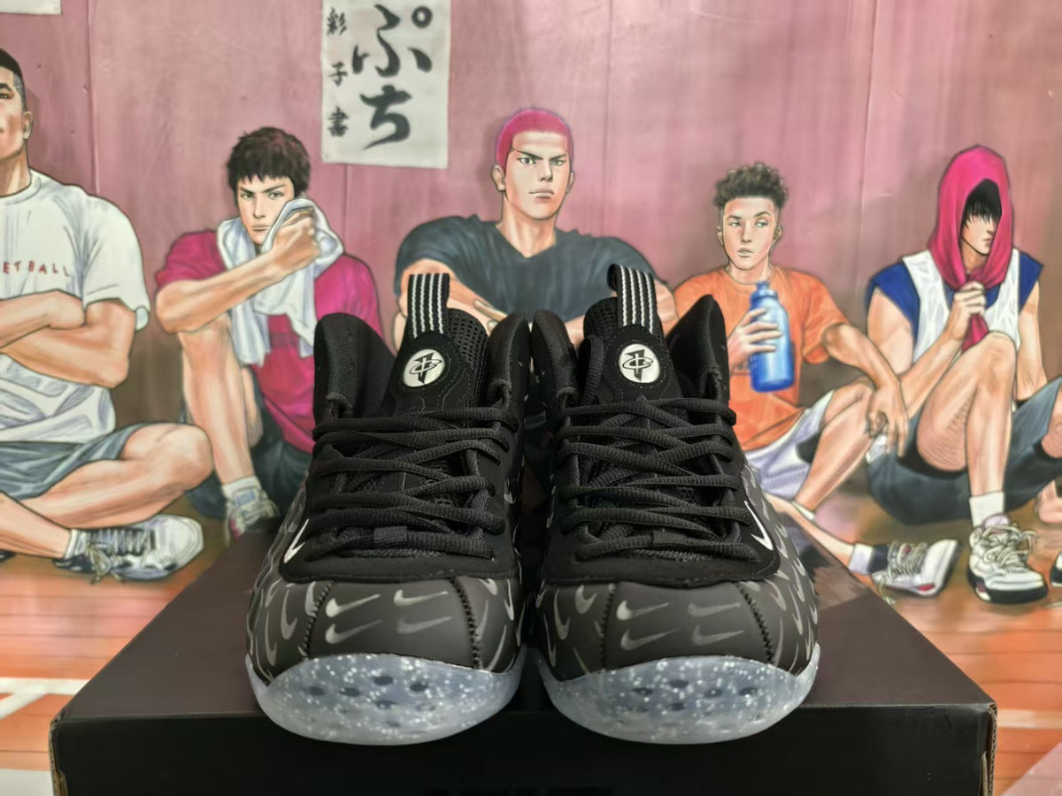 Front view of black Nike basketball sneakers with a repeating gray Swoosh pattern and translucent speckled soles.