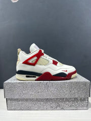 Clean side profile of a white Air Jordan 4 Retro sneaker with red structural accents and a dark navy midsole.