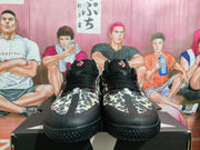 Front view of black and leopard-print Converse sneakers displayed on a shoebox.