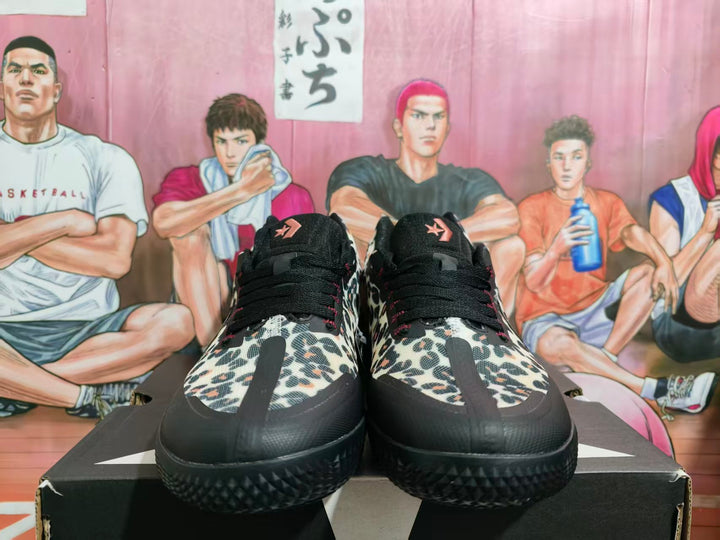 Front view of black and leopard-print Converse sneakers displayed on a shoebox.