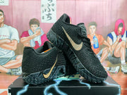 Black and gold Nike sneakers shown together, one resting across the other