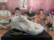 Side view of a white high-top basketball sneaker showing layered straps, a gold Swoosh-style detail, black midsole sections, and a translucent-looking outsole.
