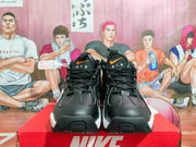 Front view of black Nike sneakers with orange Swoosh details and white outsole sections.