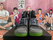 Front view of black and gray patterned high-top basketball shoes with green outsoles