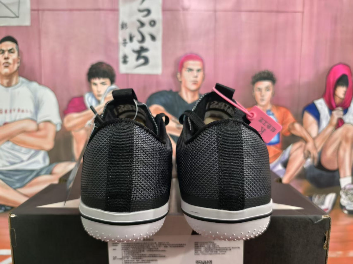 Rear view of black sneakers with white midsoles and textured white outsoles.