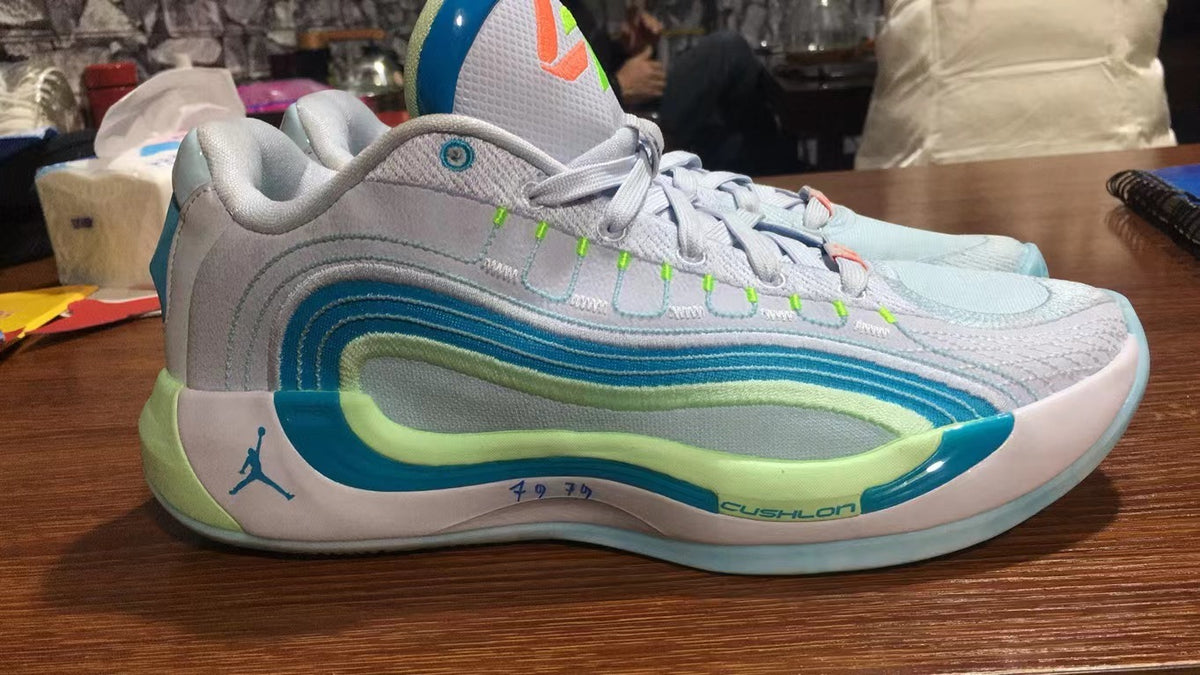 Side view of Jordan 921-1 sneakers in white, green, and blue with layered side detailing, a Jumpman logo, and a cushioned midsole.