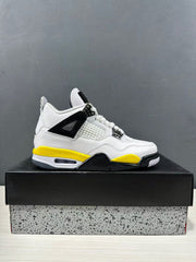 Side profile of a white, yellow, and black Jordan Air Jordan 4 sneaker displayed on a shoebox.