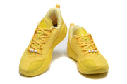 Pair of yellow low-top sneakers shown from the front with patterned uppers and white lace beads.