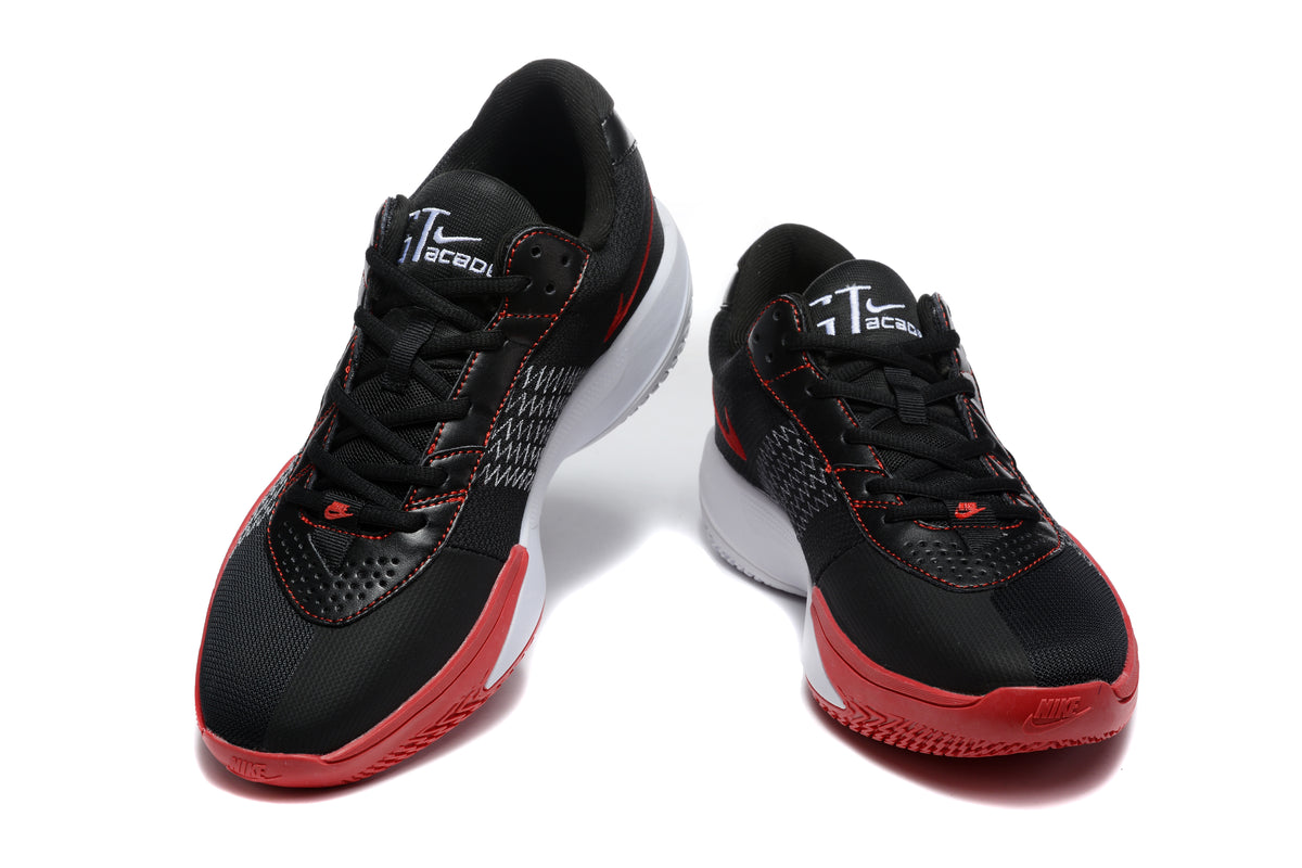Pair of black Nike basketball shoes with red outsoles, white midsoles, and red-trimmed side Swooshes shown from the front.