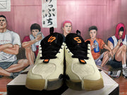 Front view of beige basketball shoes with black laces and orange tongue accents