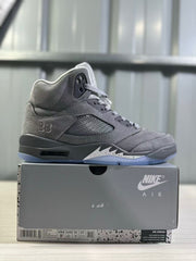 Side profile of a grey high-top sneaker displayed on its box; the box label visibly shows EU 43, US 9.5, UK 8, and CM 27.5.