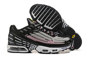 Side view of black, white, and pink Nike Air Max Plus sneakers, including the outsole and sculpted sole.