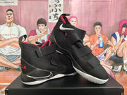 Angled view of the black and red Nike LeBron sneakers highlighting the side swoosh, adjustable straps, and white outsole.