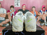Rear view of white Nike shoes with lime-green heel lettering and a textured outsole.