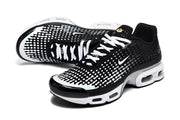 Angled view of black and white Nike Air Max Plus VII sneakers with white laces and dotted gradient uppers.