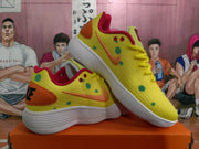 Pair of yellow sneakers displayed together, showing orange accents, green dot graphics, red collars, and white textured outsoles.