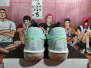 Rear view of light blue and gray Nike basketball sneakers with green accents and pink collar details.