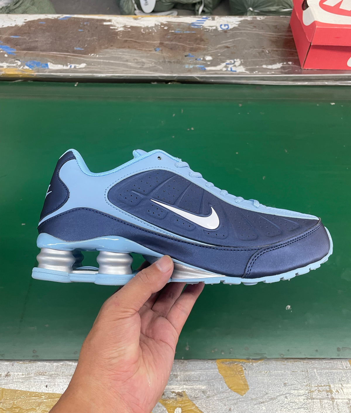 Side view of a navy and light blue Nike low-top sneaker with a white Swoosh and column-style heel cushioning.