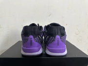 Rear view of black and purple low-top basketball shoes with purple heel panels.