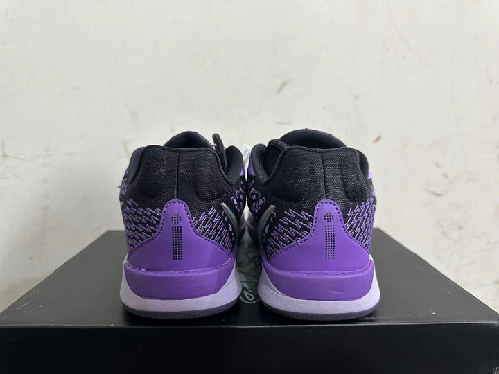 Rear view of black and purple low-top basketball shoes with purple heel panels.
