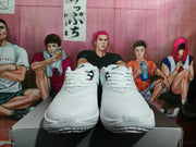 Front view of white Nike basketball sneakers with white laces, black branding, and textured soles.