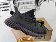 Side profile showing the black knit-style upper, lace closure, heel pull tab, and ribbed sole.
