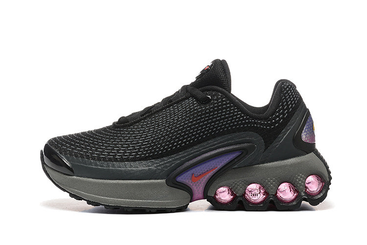Side view of black Nike Shox TL sneakers with a mesh upper and pink cushioning details.