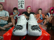 Front view of white Nike basketball sneakers with gray and black patterned toe panels and red accents, displayed on a red shoebox.
