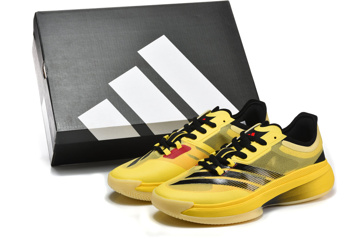 Pair of yellow and black Adidas basketball shoes beside a branded shoebox