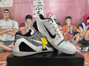 Angled view of white and black Nike Kobe basketball shoes with contrasting side logos and yellow hangtag.