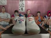 Front view of white Nike basketball sneakers showing multicolor tongues, white laces, and green toe accents.
