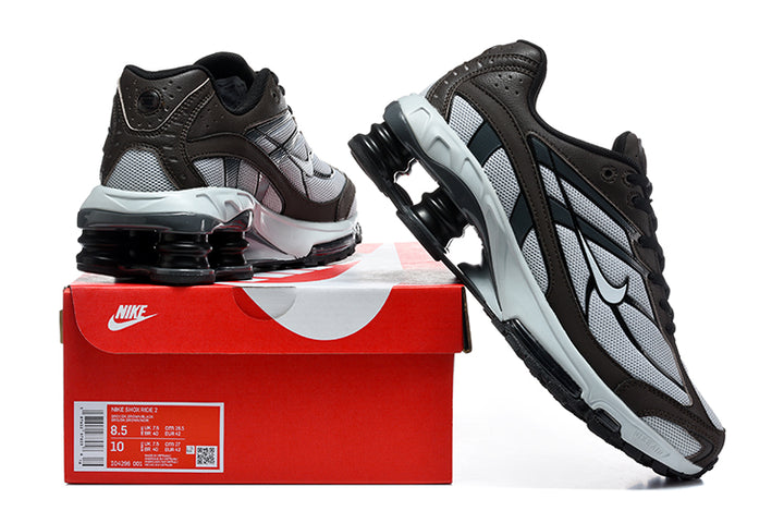 Nike Shox Ride 2 sneakers in brown, silver, and black beside a red Nike box; the box label shows a sample size.