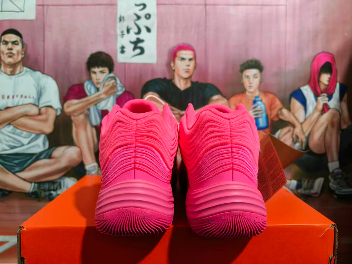 Rear view of a pair of bright pink basketball sneakers showing layered heel detailing and textured soles.