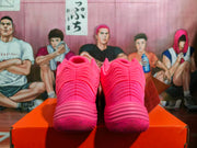 Rear view of a pair of bright pink basketball sneakers showing layered heel detailing and textured soles.