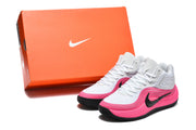 Pair of white and pink sneakers displayed beside an orange Nike-branded shoebox.