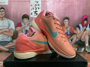 Side view of coral-orange Nike Kobe basketball shoes with teal swooshes and textured uppers.