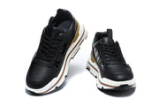 Two black lace-up sneakers shown from front angles, with perforated toe panels and white-and-brown sole detailing.