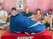 Side view of a blue Nike The Glove sneaker showing the high-top silhouette, covered upper, white side logo, and sculpted outsole.