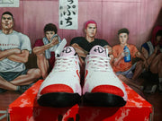 Front view of the pair showing white laces, red-orange toe accents, pink details, tongue marks, and black textured outsoles.