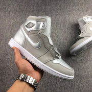 Handheld side view of a grey and silver high-top sneaker showing the ankle branding and white rubber outsole.