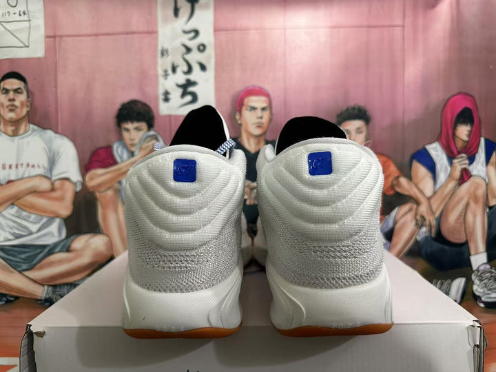 Rear view of white Nike basketball shoes with blue heel details and gum-colored outsoles.