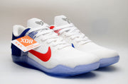 Front three-quarter view of white Kobe 11 shoes with blue and red details.