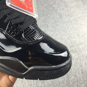 Close-up of the glossy black toe box, mesh panel, laces, and textured outsole.