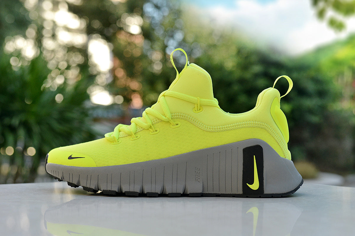 Side view of a neon yellow Nike low-top running shoe with a gray grooved sole